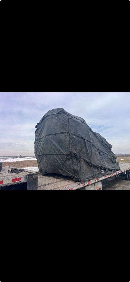 Front view of dark-tarped curved load tied down to flatdeck in winter conditions