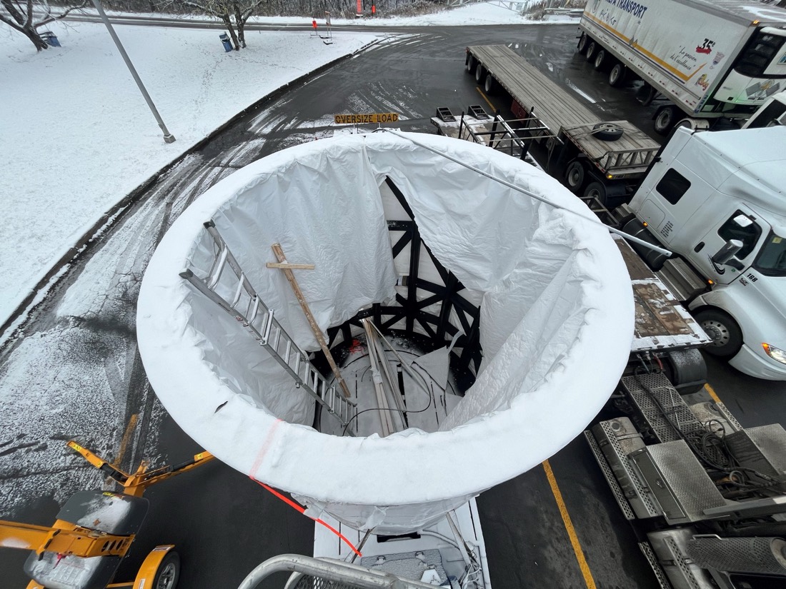 Overhead view of trommel cage on stepdeck with ladder access — white tarp wrap underway