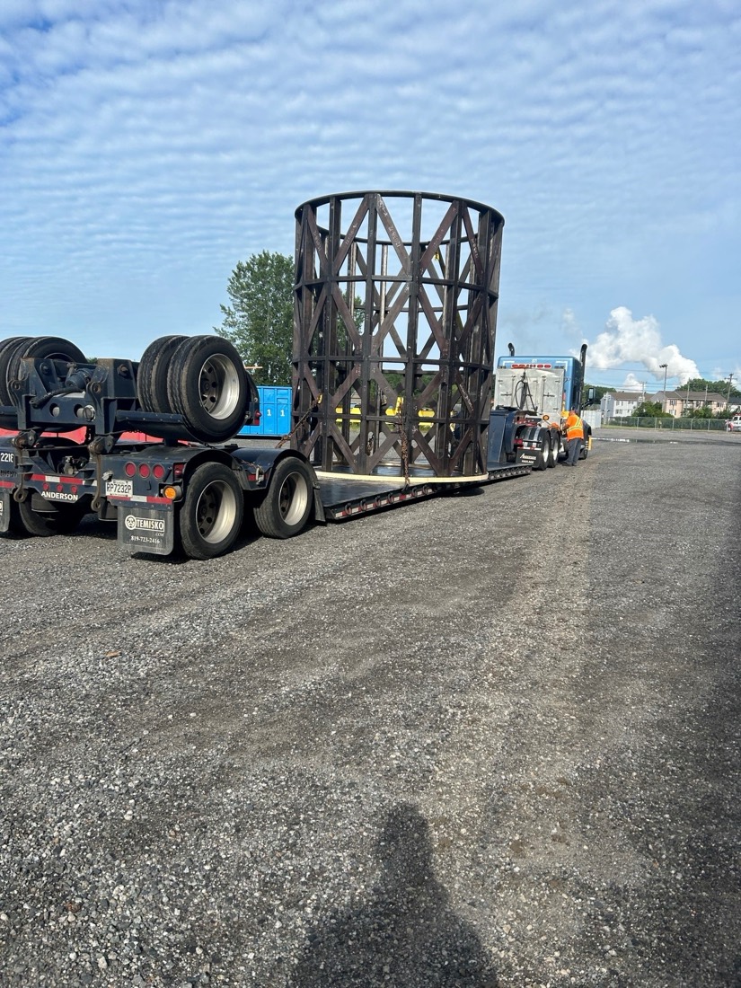 Rear quarter view of trommel cage on stepdeck rolling out of fabricator lot
