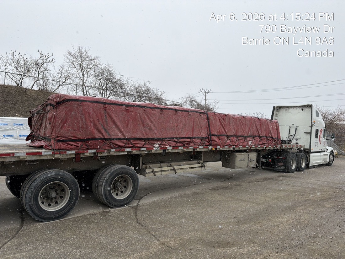 Same flatdeck after red tarp installed over bulk-bag load — Barrie ON depot