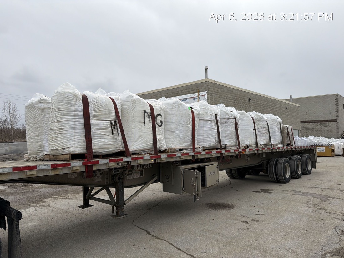 Side profile of &ldquo;MG&rdquo;-marked FIBC bulk bags strapped to tridem flatdeck at warehouse